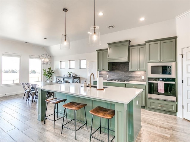 kitchen with green cabinets, a spacious island, decorative light fixtures, appliances with stainless steel finishes, and a kitchen breakfast bar