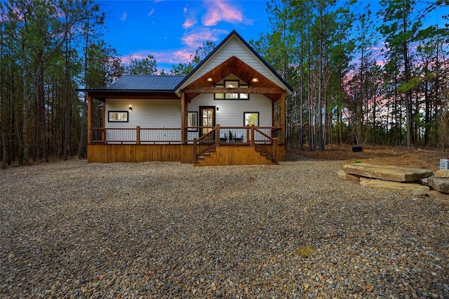 back house at dusk featuring covered porch