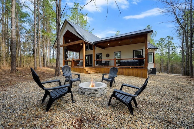 back of property featuring central air condition unit and an outdoor fire pit