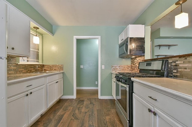 kitchen featuring appliances with stainless steel finishes, decorative light fixtures, white cabinetry, sink, and dark wood-type flooring