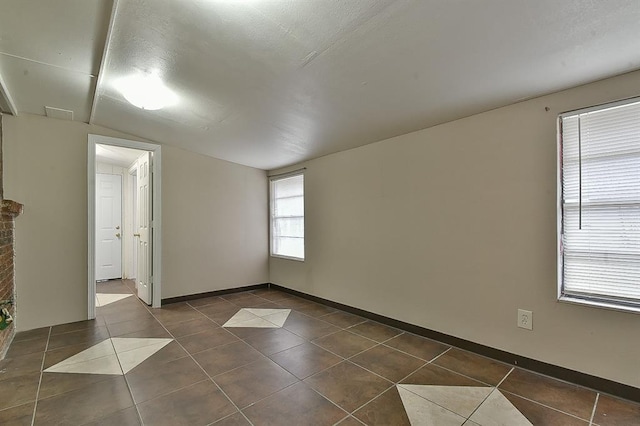 tiled spare room featuring lofted ceiling