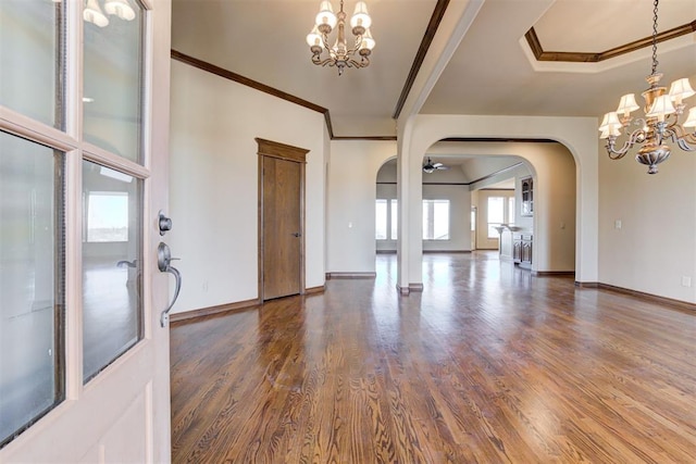 foyer entrance with ornamental molding, dark hardwood / wood-style flooring, and a notable chandelier