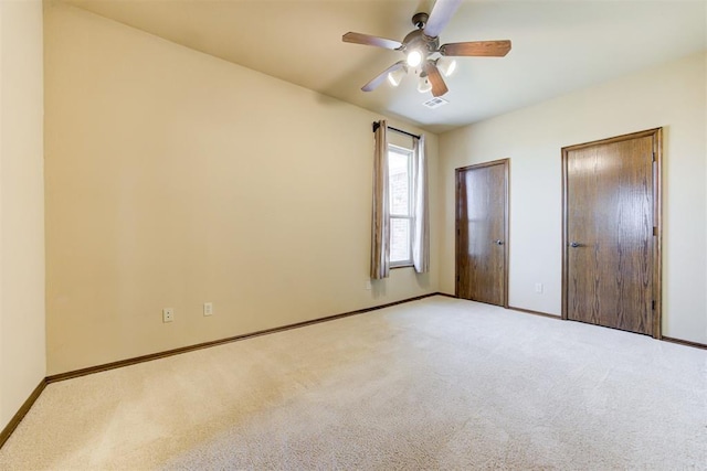 unfurnished bedroom featuring light carpet, two closets, and ceiling fan