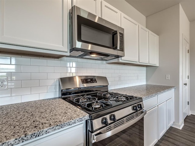13136 Mannington Rd, Edmond, OK 73025 - kitchen with appliances with stainless steel finishes, dark wood finished floors, light stone countertops, white cabinetry, and tasteful backsplash