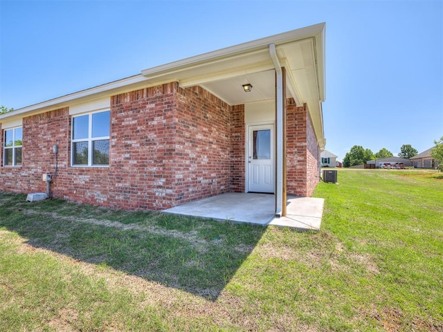 13136 Mannington Rd, Edmond, OK 73025 - back of house featuring brick siding, a yard, a patio, and cooling unit