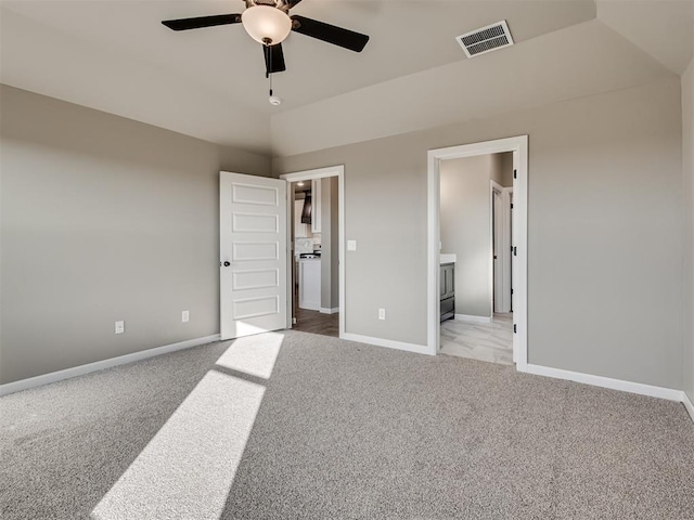 unfurnished bedroom featuring vaulted ceiling, connected bathroom, light carpet, and ceiling fan