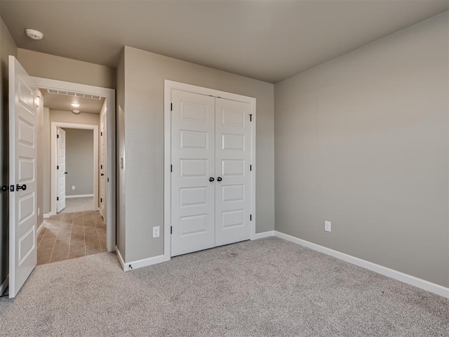 unfurnished bedroom featuring light colored carpet and a closet