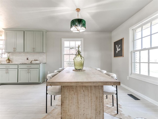 dining room featuring baseboards, plenty of natural light, light wood-style flooring, and visible vents