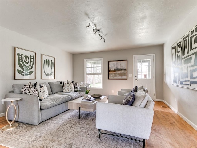 living area with plenty of natural light, light wood finished floors, and baseboards