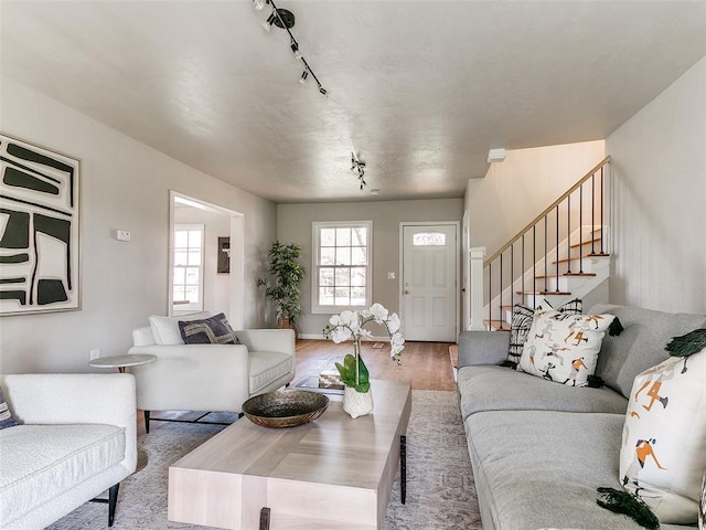 living room with track lighting, stairs, and wood finished floors