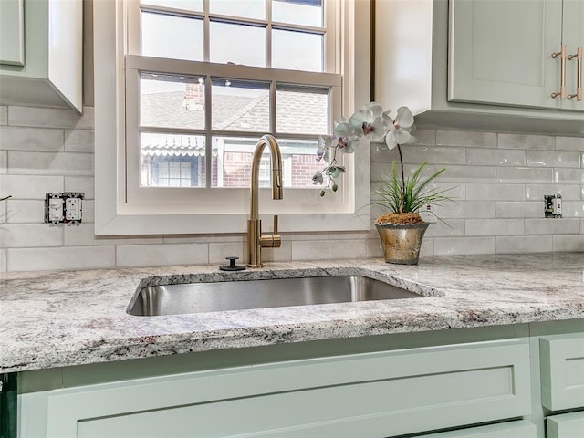 room details with light stone counters, decorative backsplash, and a sink