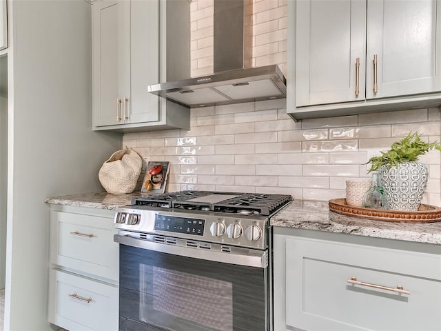 kitchen featuring wall chimney exhaust hood, backsplash, stainless steel gas range, and light stone countertops