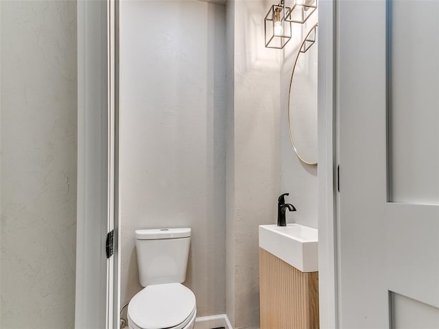 bathroom with vanity, a textured wall, and toilet