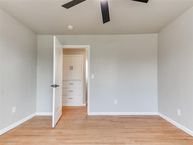 spare room featuring baseboards, ceiling fan, and light wood finished floors