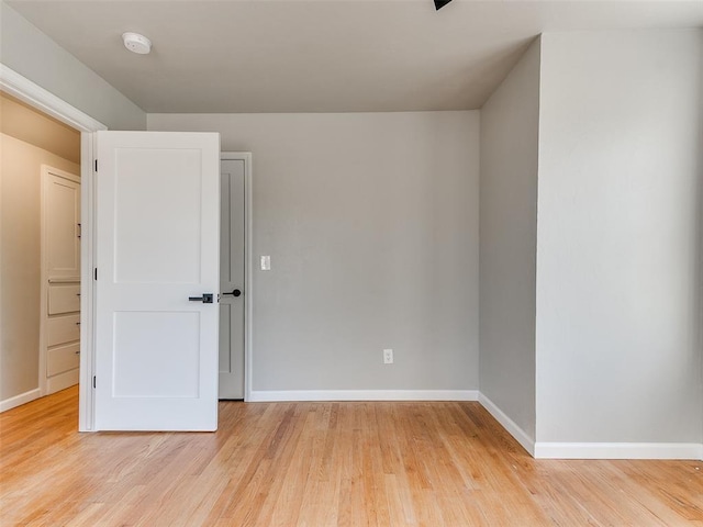 spare room with baseboards and light wood-style flooring