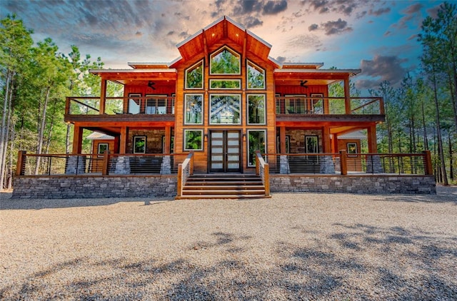 back house at dusk featuring a balcony and french doors