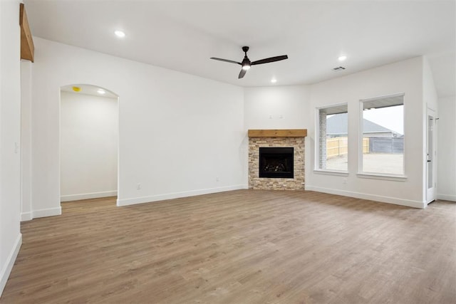 unfurnished living room with ceiling fan, a fireplace, and light wood-type flooring