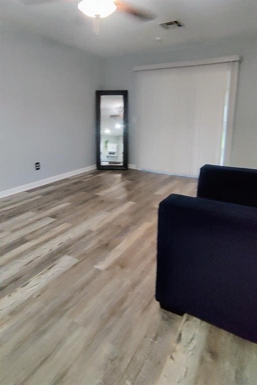 sitting room with baseboards, light wood-style flooring, visible vents, and a ceiling fan