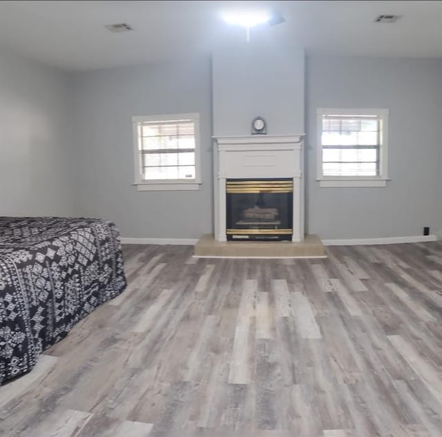 living room with a healthy amount of sunlight, a glass covered fireplace, visible vents, and wood finished floors