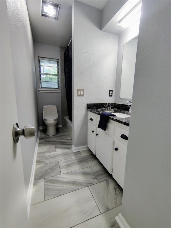 bathroom featuring toilet, marble finish floor, baseboards, a shower with shower curtain, and vanity