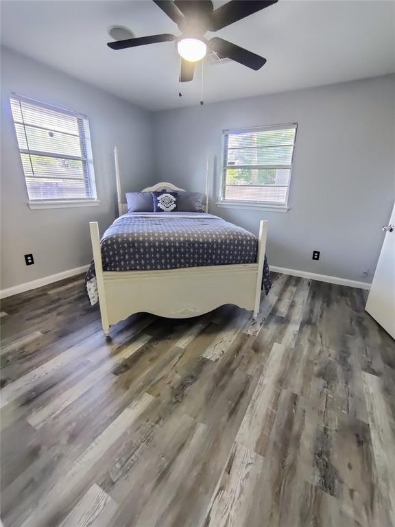 bedroom featuring baseboards, multiple windows, ceiling fan, and wood finished floors