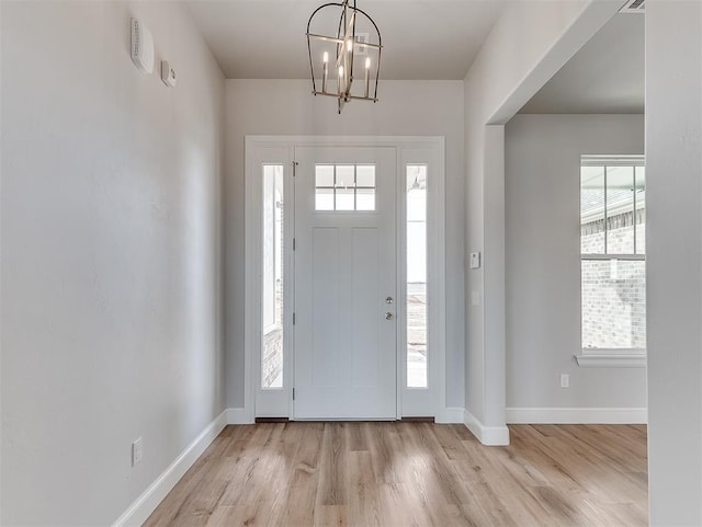 foyer with an inviting chandelier and light hardwood / wood-style flooring