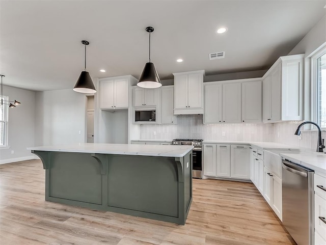 6209 Rivergate Dr, Shawnee, OK 74804 - kitchen featuring decorative light fixtures, a kitchen island, white cabinets, and appliances with stainless steel finishes