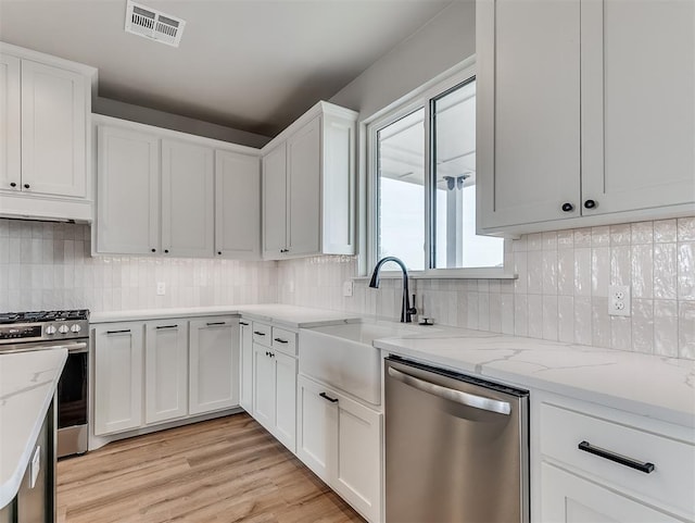 6209 Rivergate Dr, Shawnee, OK 74804 - kitchen featuring stainless steel appliances, white cabinetry, light stone countertops, and light hardwood / wood-style floors