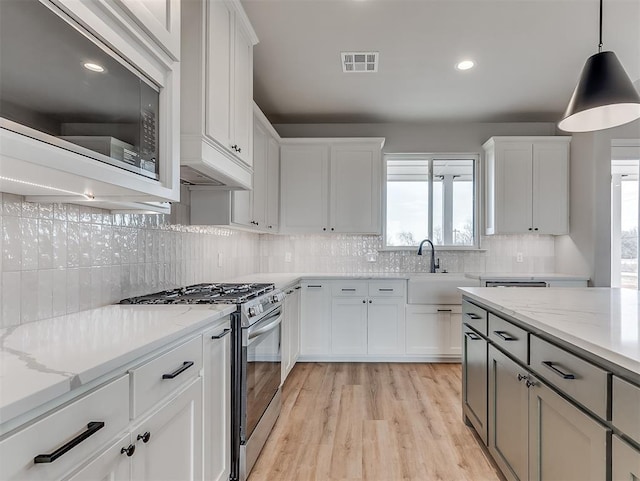 6209 Rivergate Dr, Shawnee, OK 74804 - kitchen with white cabinetry, decorative light fixtures, stainless steel gas range, and light stone counters