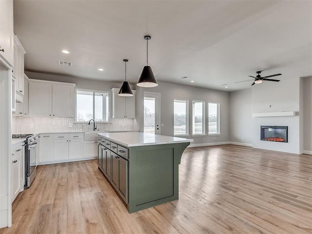 6209 Rivergate Dr, Shawnee, OK 74804 - kitchen with white cabinetry, gas stove, a kitchen island, and backsplash