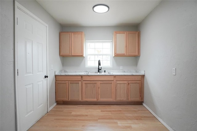 kitchen with sink, light hardwood / wood-style floors, and light stone countertops