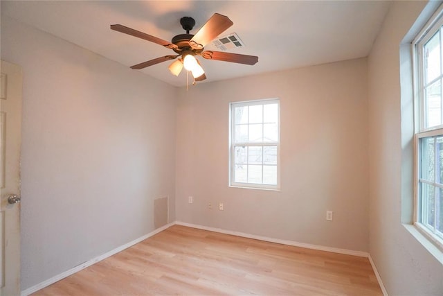 empty room featuring plenty of natural light, ceiling fan, and light wood-type flooring