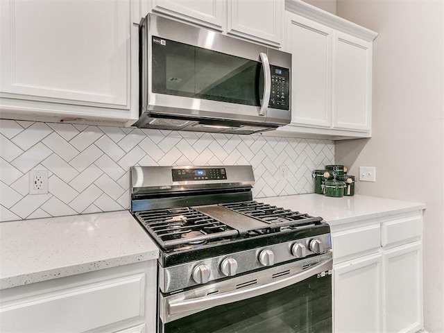 kitchen featuring appliances with stainless steel finishes, light stone counters, white cabinets, and backsplash