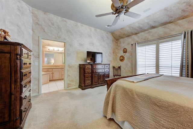 bedroom with connected bathroom, light colored carpet, and ceiling fan