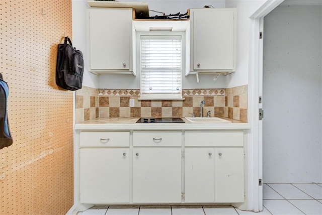 kitchen with light tile patterned floors, black electric stovetop, sink, and white cabinets