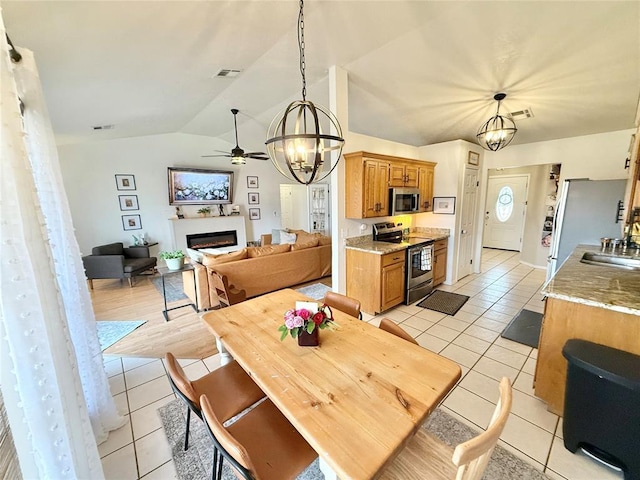 tiled dining space with ceiling fan with notable chandelier, sink, and vaulted ceiling