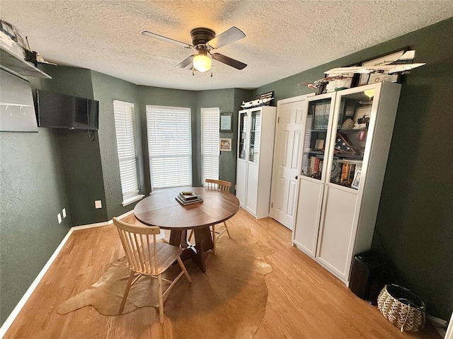 dining space featuring a textured ceiling, ceiling fan, and light wood-type flooring