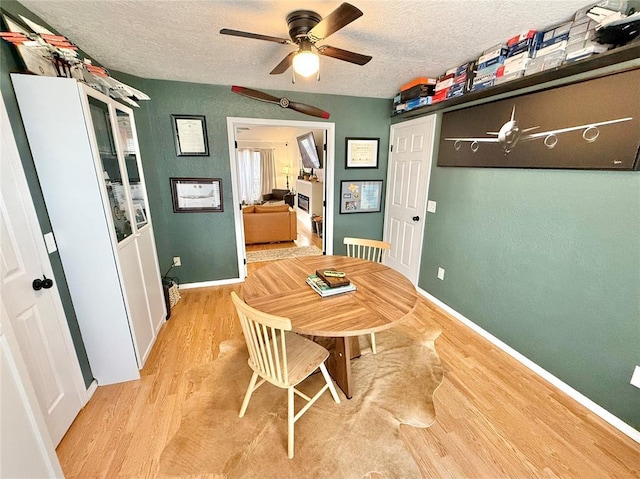 dining space with ceiling fan, a textured ceiling, and light wood-type flooring