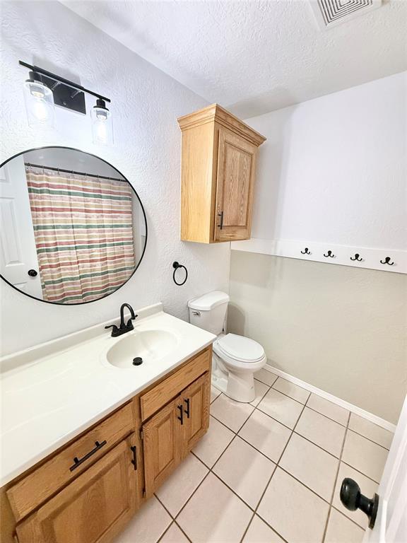 bathroom with vanity, tile patterned flooring, toilet, and a textured ceiling