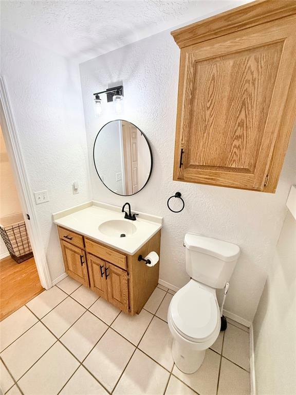 bathroom featuring tile patterned floors, toilet, vanity, and a textured ceiling