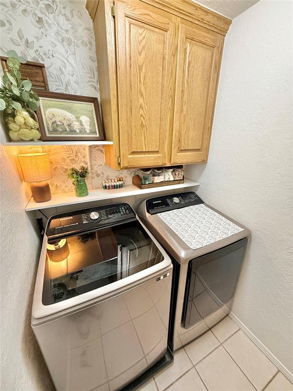 laundry room featuring light tile patterned floors, washing machine and dryer, and cabinets