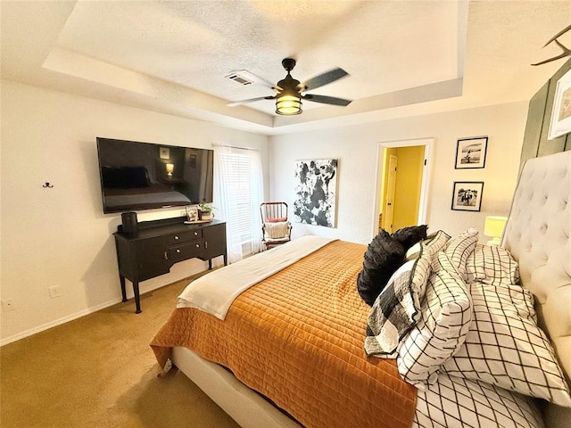 bedroom featuring ceiling fan, a raised ceiling, a textured ceiling, and carpet flooring