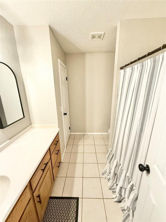 bathroom featuring vanity, tile patterned floors, and a textured ceiling