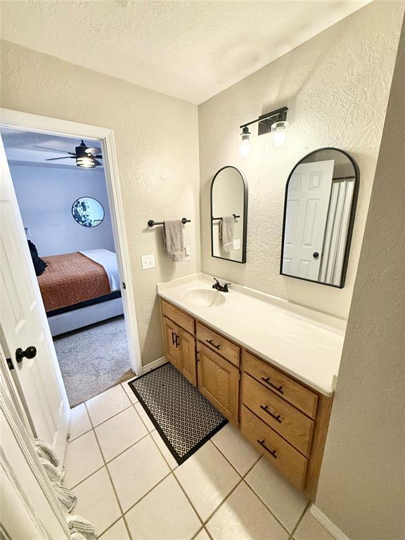 bathroom featuring tile patterned flooring, vanity, ceiling fan, and a textured ceiling