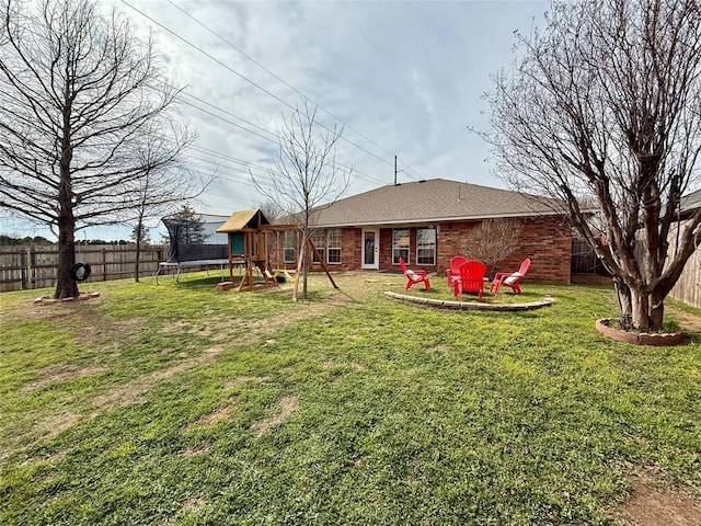 view of yard with a trampoline, a playground, and an outdoor fire pit