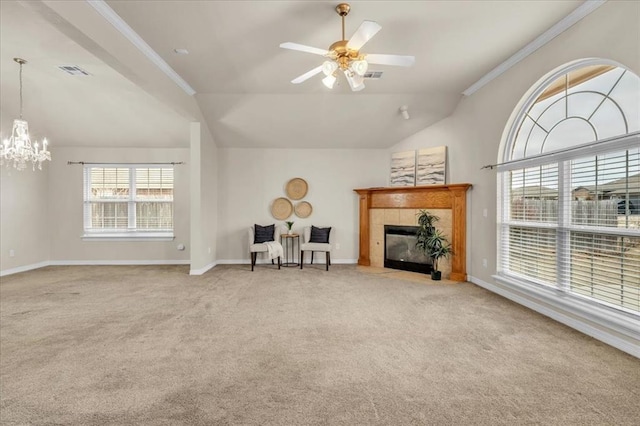 carpeted living room with ceiling fan with notable chandelier, ornamental molding, a tiled fireplace, and vaulted ceiling