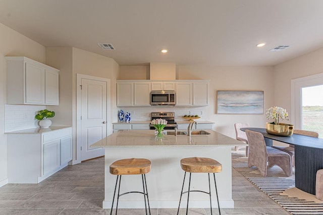 kitchen with visible vents, a kitchen island with sink, appliances with stainless steel finishes, and white cabinets