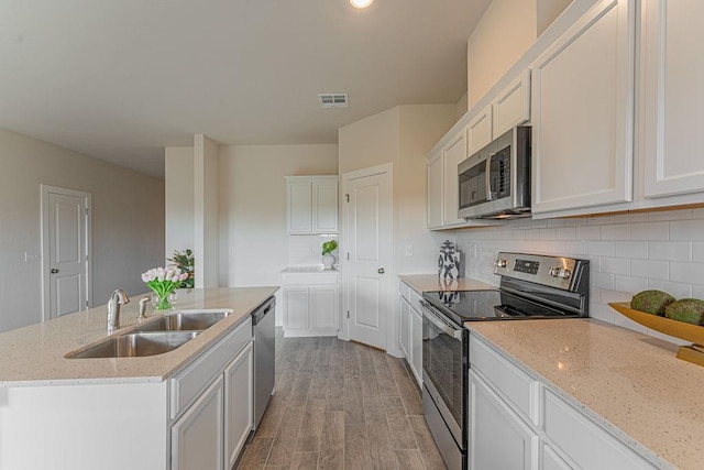 kitchen featuring appliances with stainless steel finishes, light wood-type flooring, a sink, and backsplash