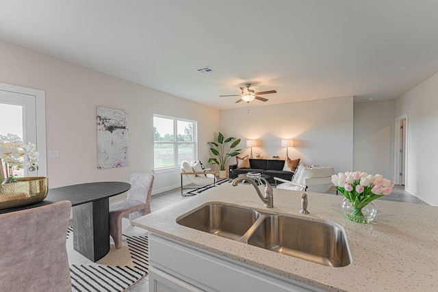 kitchen featuring open floor plan, visible vents, a sink, and light stone countertops