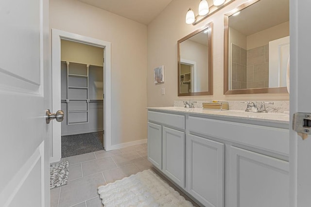 full bathroom with baseboards, double vanity, a sink, and tile patterned floors